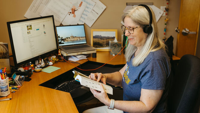 a woman with headphones sitting at a desk reading