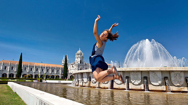 Girl jumping in front of fountain, Belem, Lisbon, Portugal