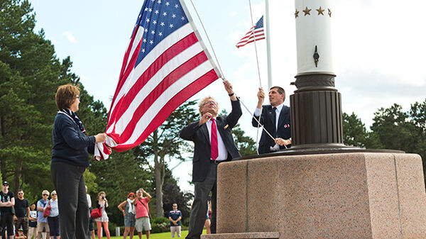 Three people raising the American flag