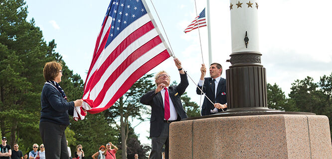 Three people raising the American flag