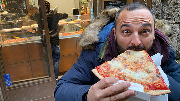 Man eating a slice of pizza, Florence, Italy