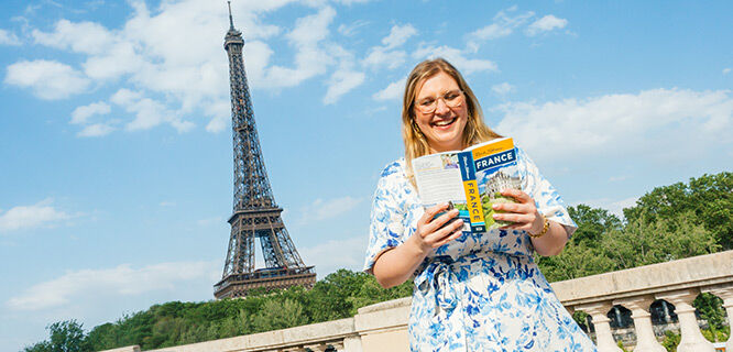 Lady holding France guidebook by the Eiffel Tower, Paris