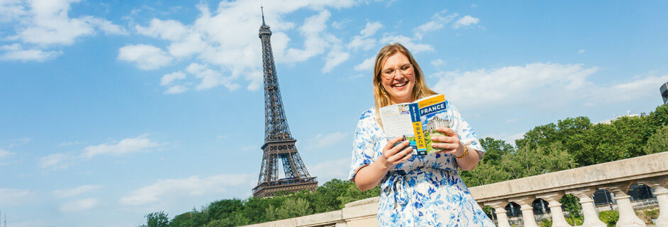 Lady holding France guidebook by the Eiffel Tower, Paris
