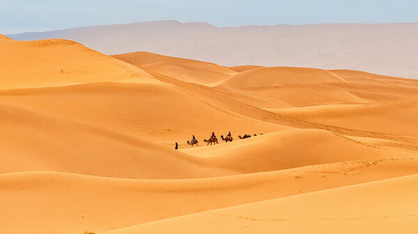 Sand dunes and camelback riders, Sahara Desert, Morocco